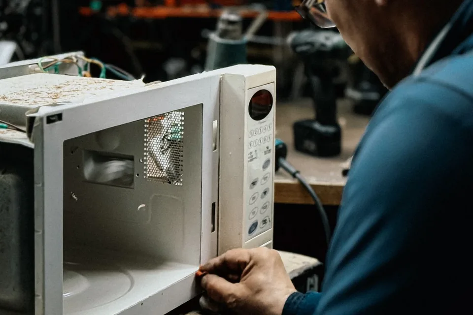 Técnico consertando micro-ondas em bancada de oficina